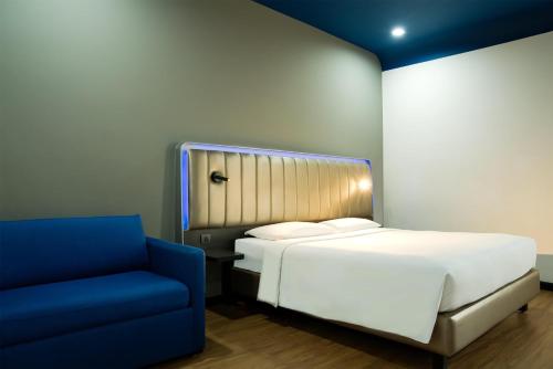 a bedroom with a bed and a blue chair at Park Inn By Radisson Amritsar Airport in Amritsar