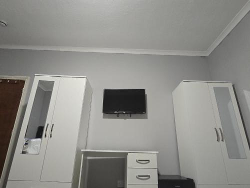 a room with white cabinets and a tv on the wall at Heathrow roomzzzz BnB in Hayes