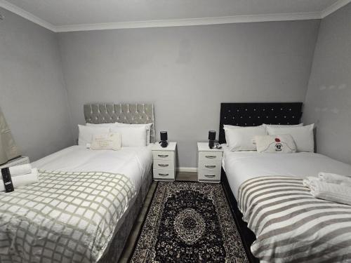 two twin beds in a room with white walls at Heathrow roomzzzz BnB in Hayes