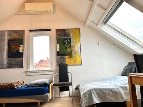 una camera da letto con un letto, una sedia e finestre di Zolderstudio dichtbij Goffert met eigen badkamer en WC, eigen keuken, eigen ingang a Nijmegen