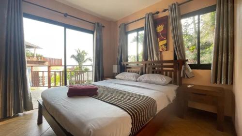 ein Schlafzimmer mit Bett und großen Fenstern in der Unterkunft Little Hill in Haad Rin