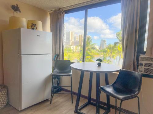 una cucina con frigorifero bianco, tavolo e sedie di Happy Hawaiian Monarch Studio condo a Honolulu