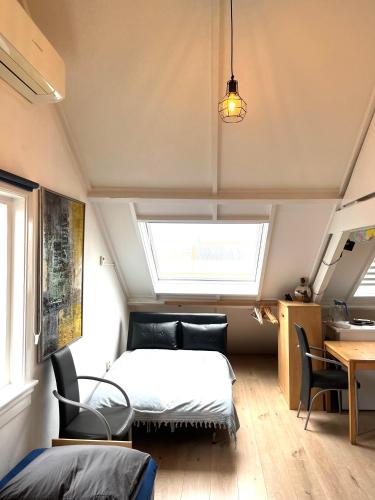 a bedroom with a bed and a table and chairs at Zolderstudio dichtbij Goffert met eigen badkamer en WC, eigen keuken, eigen ingang in Nijmegen