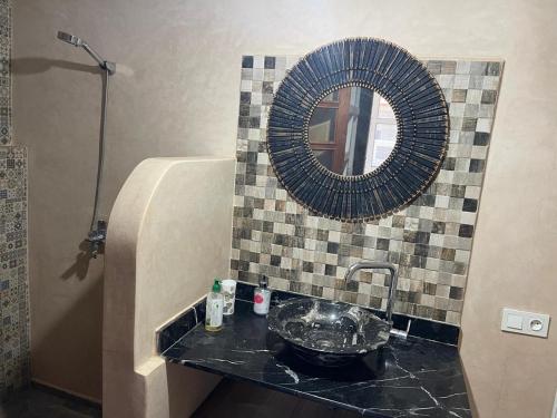ein Badezimmer mit Waschbecken und Spiegel in der Unterkunft Riad Eglantine in Touggana