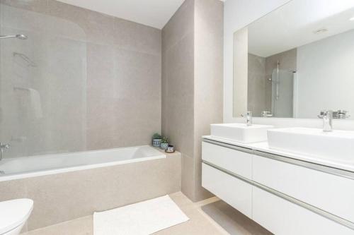 a bathroom with two sinks and a tub and a toilet at New 2bedroom Apartment w Terrace & Infinity Pool in Olhos de Água