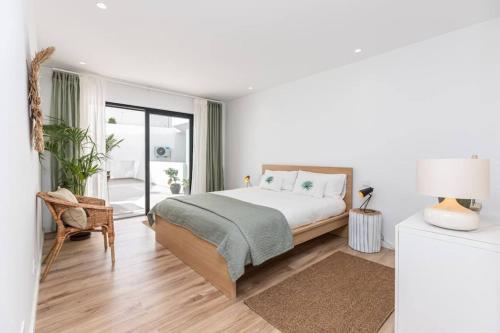 a white bedroom with a bed and a balcony at New 2bedroom Apartment w Terrace & Infinity Pool in Olhos de Água