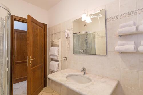 un bagno con lavandino, specchio e asciugamani di Il Girasole - Corbezzolo a Venturina Terme