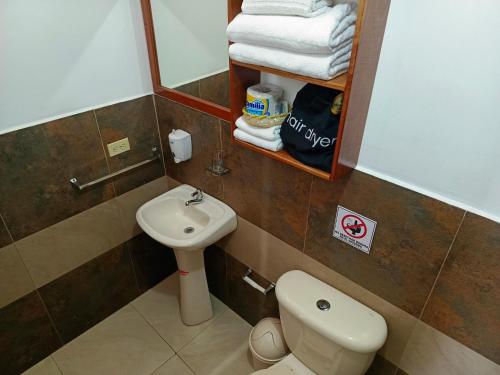 een badkamer met een toilet, een wastafel en een spiegel bij Tesita's House habitación doble in Puerto Baquerizo Moreno