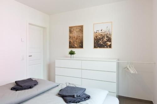 a white bedroom with two beds and a dresser at Apartment unter den Kiefern 93 in Röbel