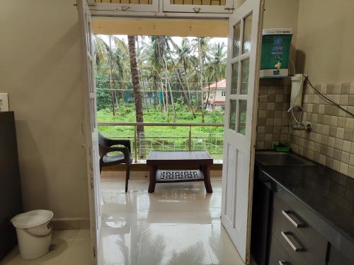 a kitchen with a door open to a balcony with a table at Guesthouse Sakina Colva in Colva