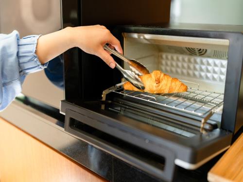 a person is cooking food in an oven at Hotel Resol Ueno in Tokyo