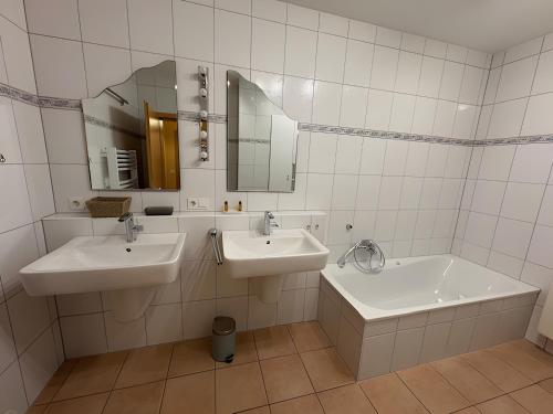 een badkamer met 2 wastafels, een bad en een spiegel bij Ferienwohnung Ruhrtal in Bestwig
