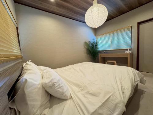 a bedroom with a bed with white sheets and a lamp at 精神と時の宿 in Nose
