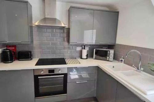eine Küche mit Herd oberer Ofen neben einer Spüle in der Unterkunft Relaxing 1 bed apartment on Tetbury High St in Tetbury