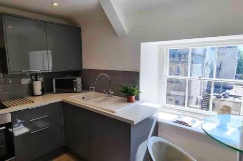 eine Küche mit Spüle und Fenster in der Unterkunft Relaxing 1 bed apartment on Tetbury High St in Tetbury