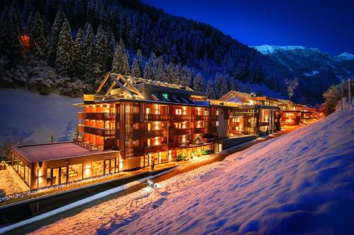 a hotel in the snow at night in the mountains at ZillergrundRock Luxury Mountain Resort in Mayrhofen