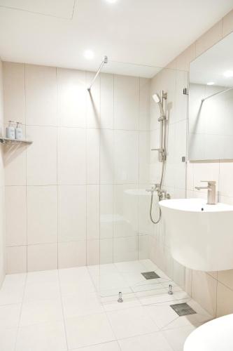 a white bathroom with a sink and a shower at Morf Stay in Seoul