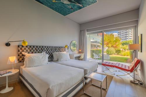 Pestana Alvor South Beach Premium Suite Hotel في ألفور: غرفة نوم بها سريرين ونافذة كبيرة