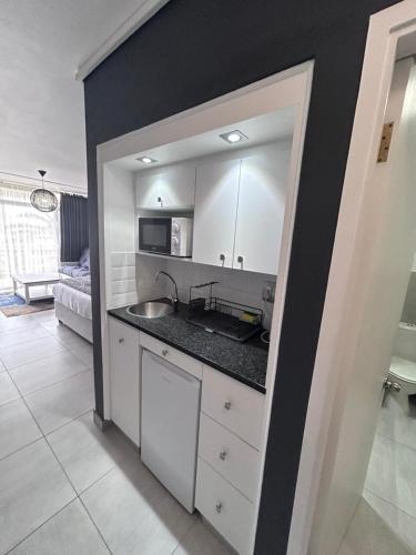 a kitchen with white cabinets and a black wall at Brookes Hill Suites Bay Watch in Gqeberha