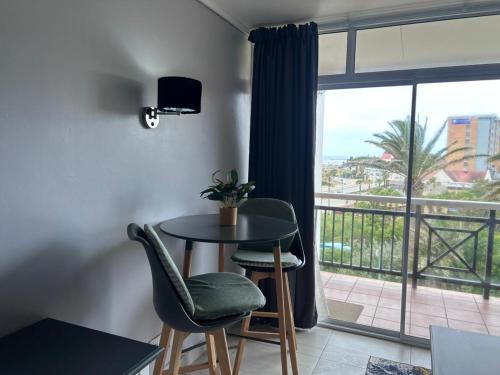 ein Zimmer mit Tisch und Stühlen und einem Balkon in der Unterkunft Brookes Hill Suites Bay Watch in Summerstrand