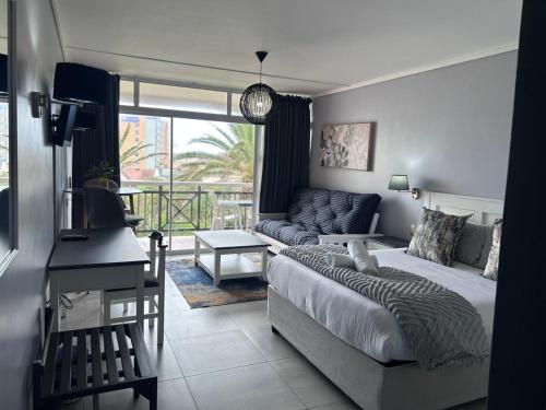 ein Schlafzimmer mit einem Bett, einer Couch und einem Tisch in der Unterkunft Brookes Hill Suites Bay Watch in Summerstrand