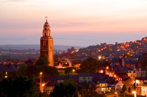 a clock tower towering over a city at night at Maldron Hotel Shandon Cork City in Cork