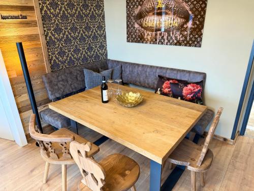 a wooden table with chairs and a bottle of wine on it at Appartement Sissi in Altmünster