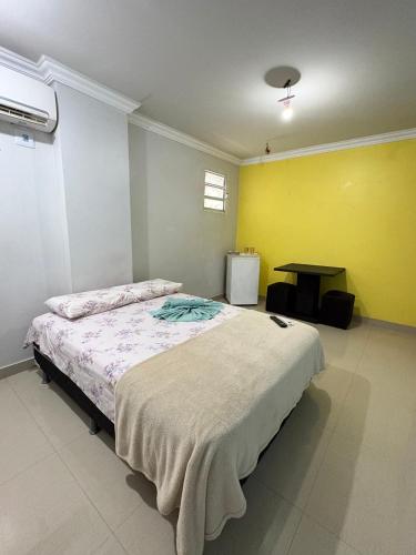 a bedroom with a bed and a yellow wall at Quarto privado próximo ao centro 10 in Manaus