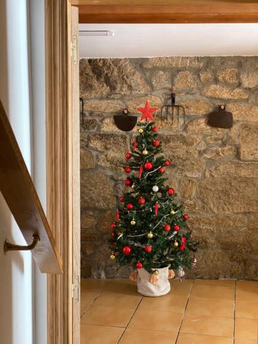 Un árbol de Navidad frente a un muro de piedra. en CASA do CAMPO Lestrove, en Padrón