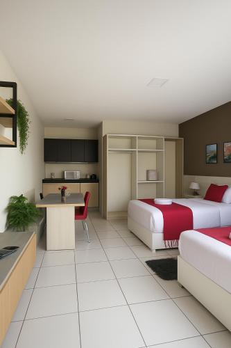 a hotel room with two beds and a kitchen at Residencial New Stilo-Falésia in Canoa Quebrada