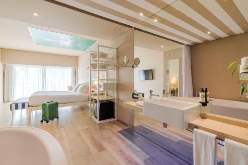 Pestana Alvor South Beach Premium Suite Hotel في ألفور: حمام مع حوض ومغسلة وسرير