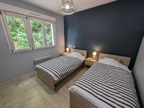 deux lits dans une chambre avec deux fenêtres dans l'établissement Le liez, à Peigney