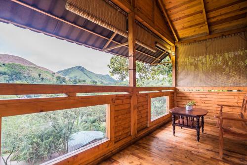 a room with large windows and a table in the middle at Holiday Vagamon in Vagamon