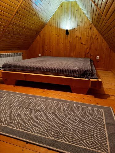 Будинок під Менчулом في راخيف: سرير في غرفة خشبية مع سجادة