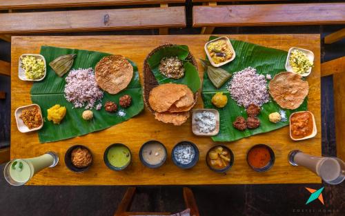 een tafel vol groene borden met verschillende soorten eten bij Zostel Homes Kumta in Kumta
