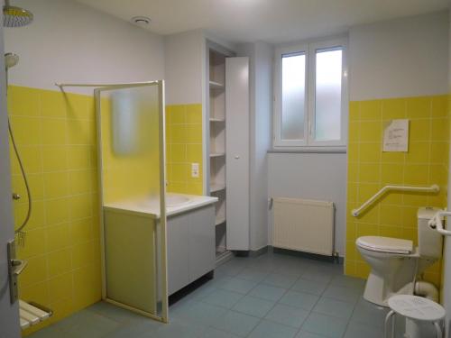 een badkamer met gele tegels, een wastafel en een toilet. bij Le relais jeanne d'arc in Cirfontaines-en-Ornois