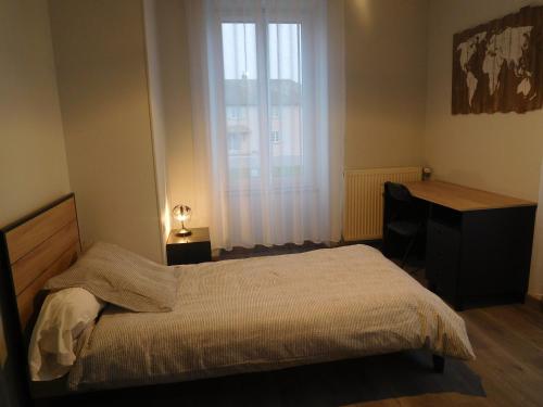 een slaapkamer met een bed, een bureau en een raam bij Le relais jeanne d'arc in Cirfontaines-en-Ornois