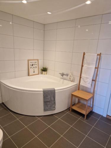 a bath tub in a bathroom with a wooden chair at Modern condominium in Bergen