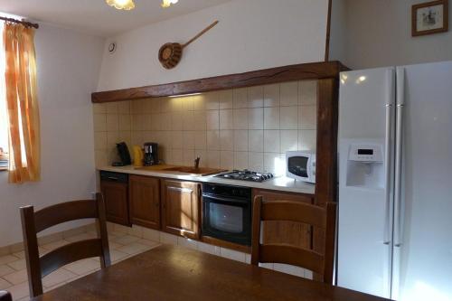 a kitchen with a stove and a refrigerator at Le cèdre bleu in Goncourt