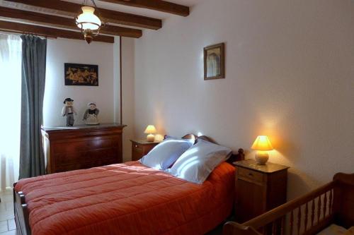 Schlafzimmer mit einem Bett mit orangefarbener Bettwäsche und weißen Kissen in der Unterkunft Le cedre bleu in Goncourt