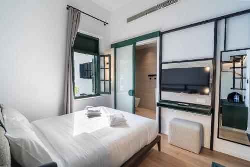 a bedroom with a white bed and a large tv at Kentrikon 1924 Boutique Hotel, Old Town in Paphos City