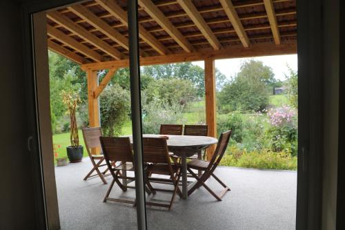 eine Terrasse mit Tisch und Stühlen unter einer Pergola in der Unterkunft Gite de la fontaine in Saint-Blin