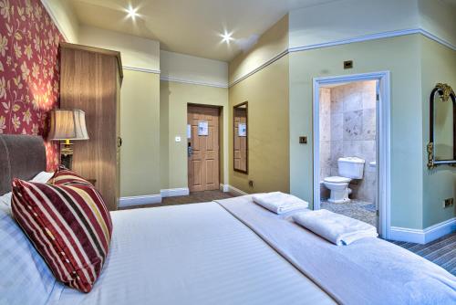a bedroom with a large bed and a bathroom at George of Piercebridge in Piercebridge