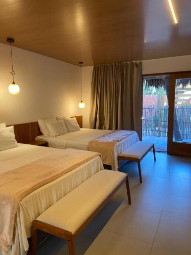 a hotel room with two beds and a window at Atins Beach Studios - Charmoso e Aconchegante in Atins