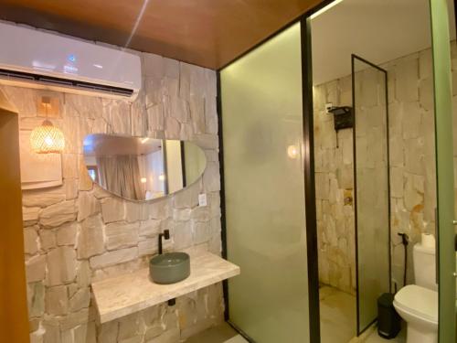 a bathroom with a stone wall and a mirror at Atins Beach Studios - Charmoso e Aconchegante in Atins