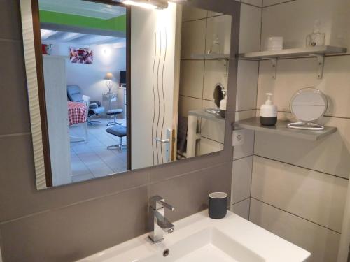 een badkamer met een wastafel en een spiegel en een kamer bij La p'tite cuisine in Faverolles