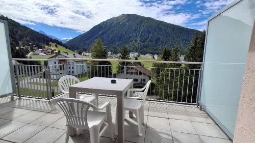 a balcony with a table and chairs and a mountain at Apartment Bünda in Davos