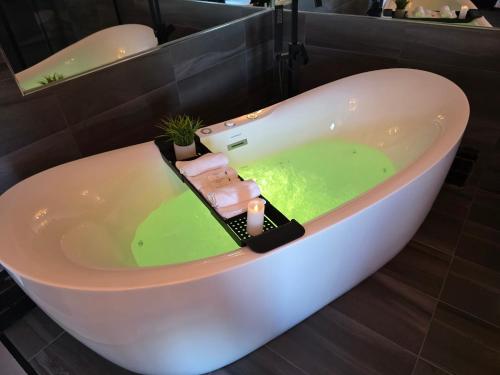 a bath tub filled with green water in a bathroom at Motel Rimouski in Rimouski