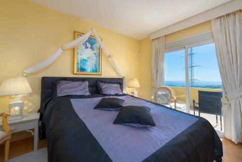 een slaapkamer met een groot bed met een groot raam bij Villa Roca Penthouse in Estepona