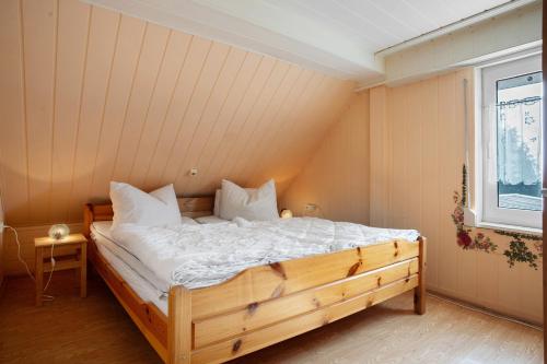 - une chambre avec un lit en bois avec des draps blancs et une fenêtre dans l'établissement Ferienhaus Am Darß - Kogge, à Pruchten